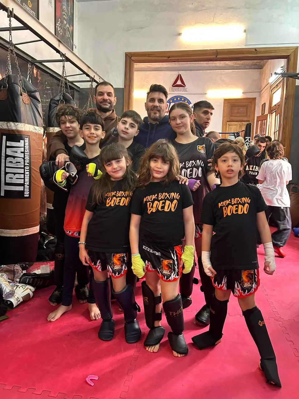 Niños y niñas de Kick Boxing Boedo con remeras del equipo, protecciones y guantes, junto a sus profesores